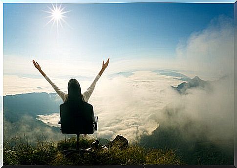 Woman has a happy life where she sits in a chair on top of a mountain