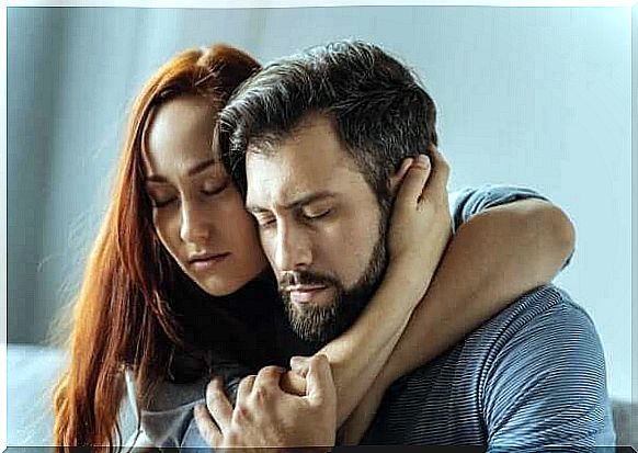 A red-haired young woman and a dark-haired man embrace each other