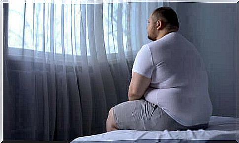 An overweight man sitting on a bed.