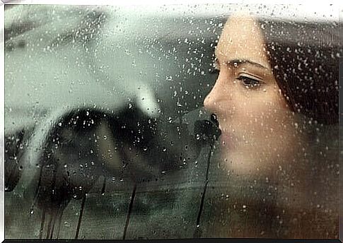 Woman behind window with rain