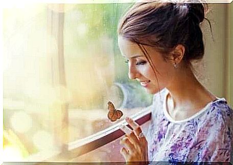 A woman looking at a butterfly in a window.