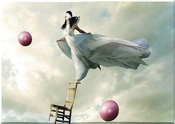 Woman balancing on a chair with pink balls in the air