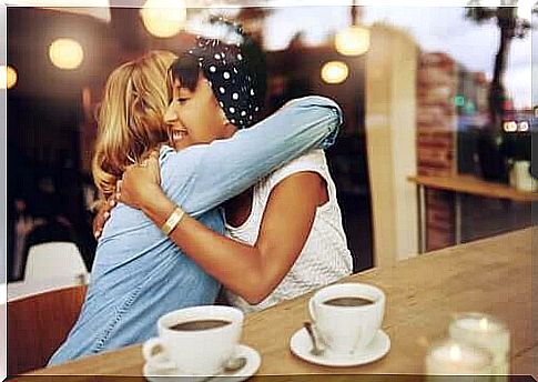 Two girlfriends give each other a real hug at a café