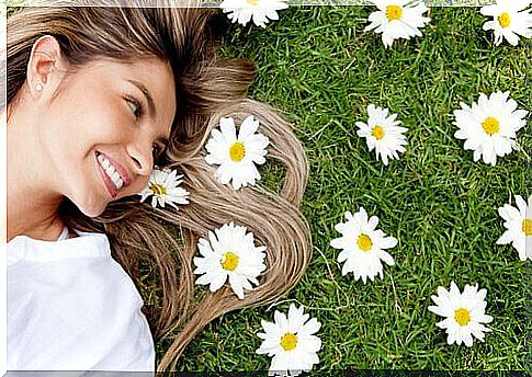 A woman lying next to flowers and smiling