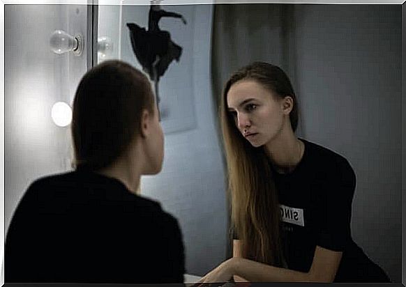 A sad woman looks in the mirror